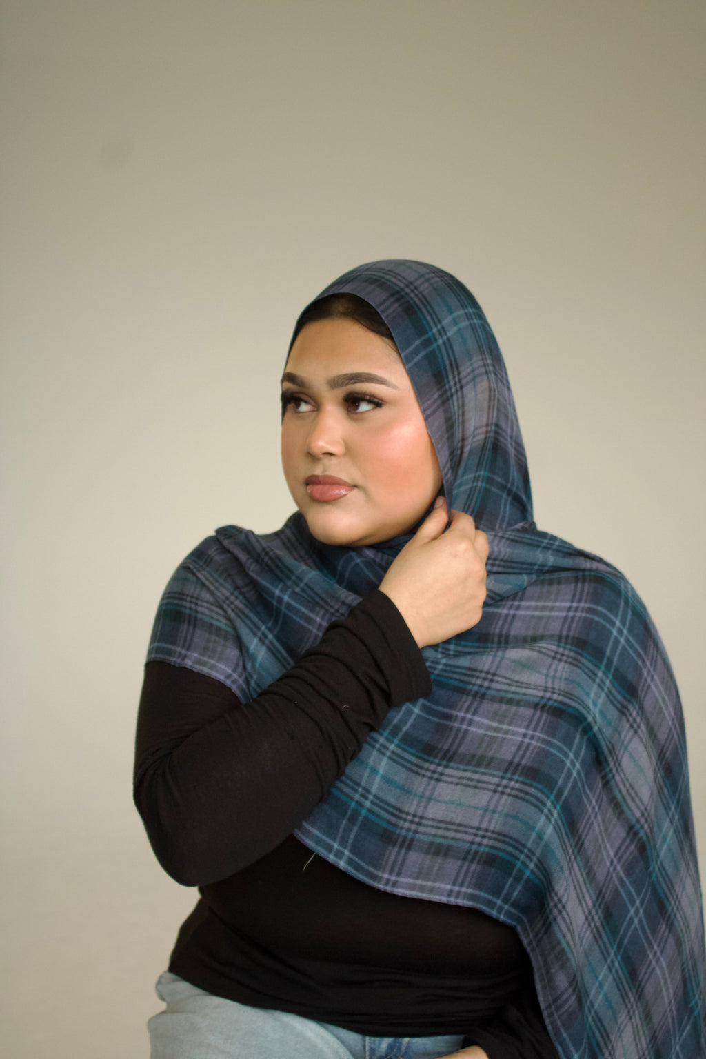Woman wearing a blue plaid shawl against a plain background