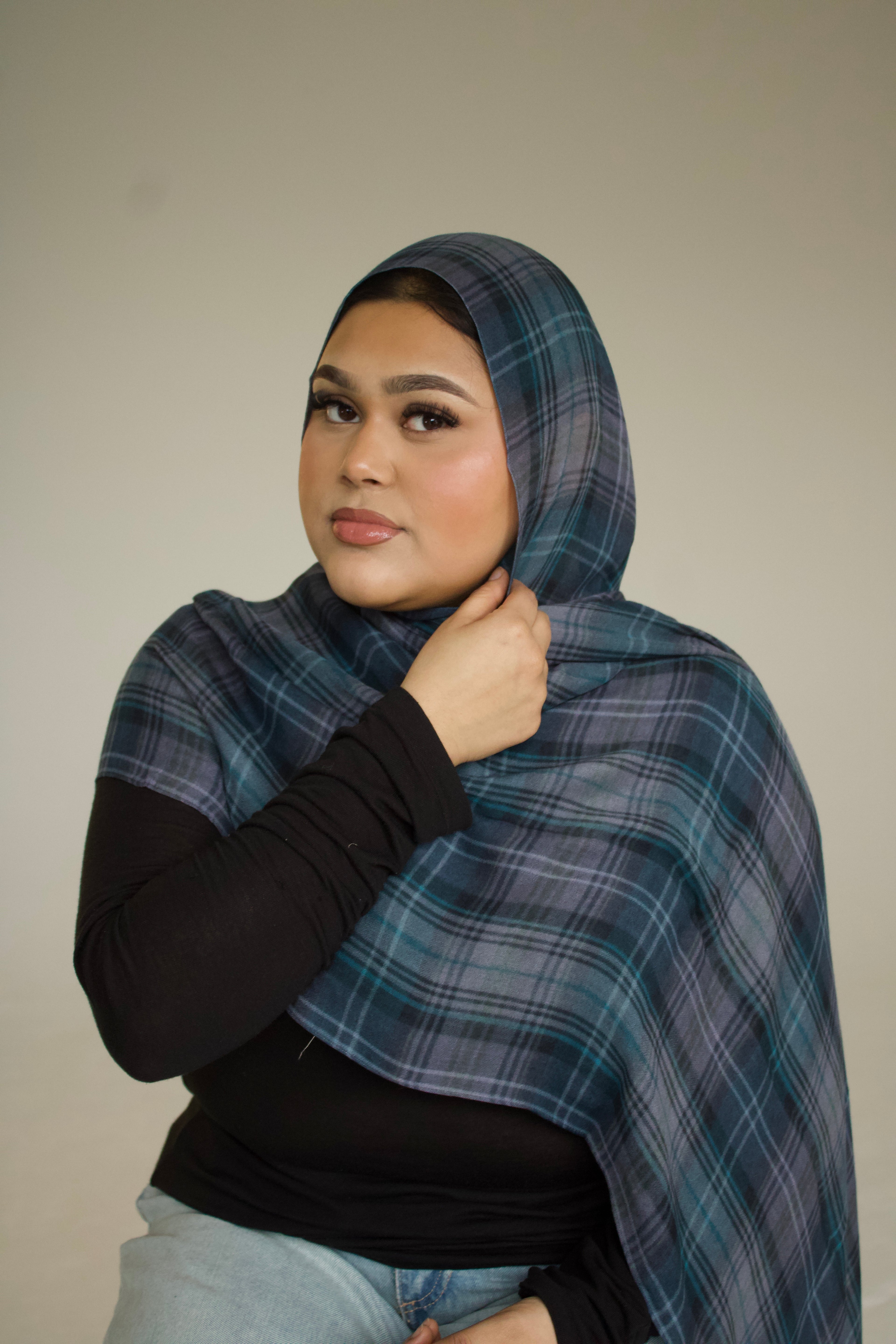 Woman wearing a blue plaid shawl against a plain background