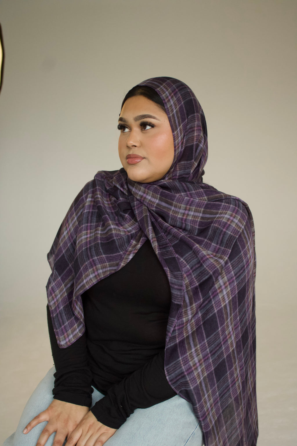 Woman wearing a purple plaid hijab against a plain background