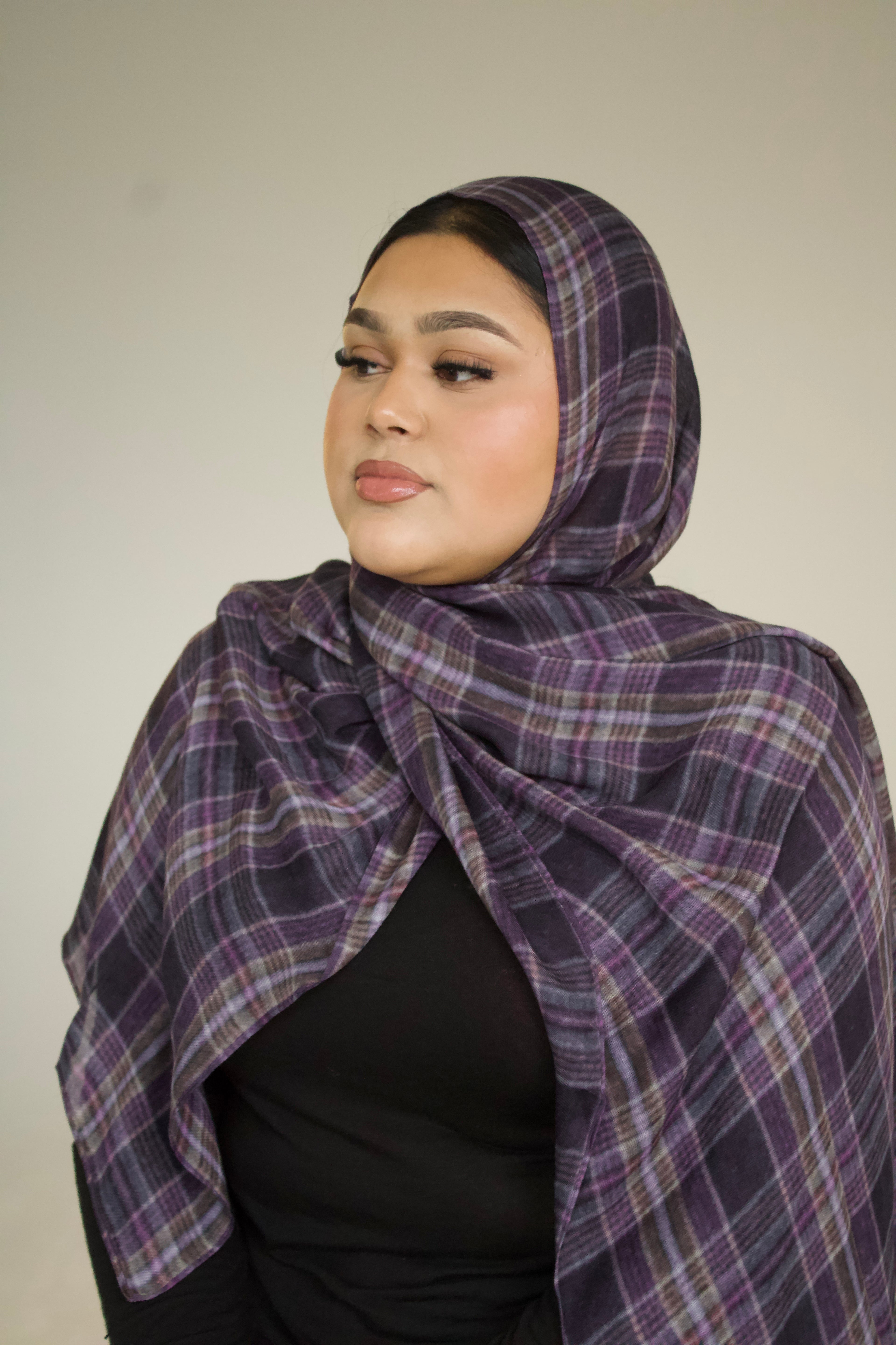 Woman wearing a purple plaid hijab against a plain background